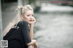 A woman with blonde hair leaning against a railing.