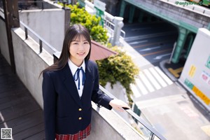 A young woman in a school uniform sitting on the floor.