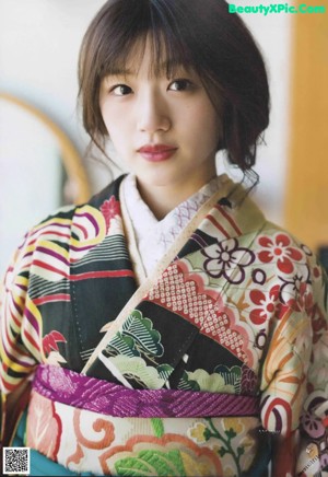 A woman in a colorful kimono poses for a picture.