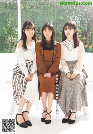 A group of three young women sitting on top of a bed.
