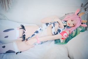 A woman in a cow costume is posing on a bed.