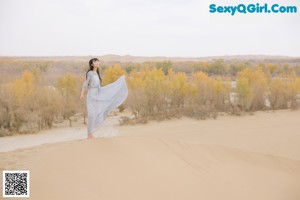 A woman in a blue dress laying on the ground.