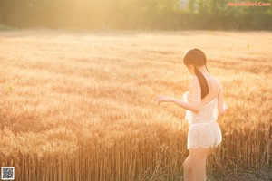 A woman in a white lingerie standing in a field.