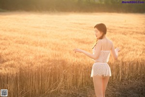 A woman in a straw hat standing in a field.