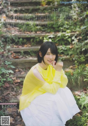 A woman in a yellow sweater and white skirt posing for a magazine.