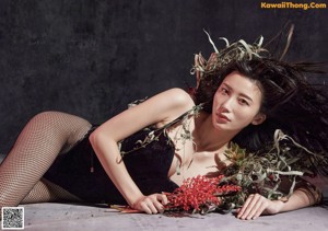 A woman laying on the ground holding a bunch of red flowers.