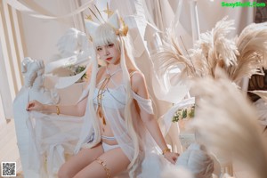 A woman with long white hair wearing a white dress and a crown.