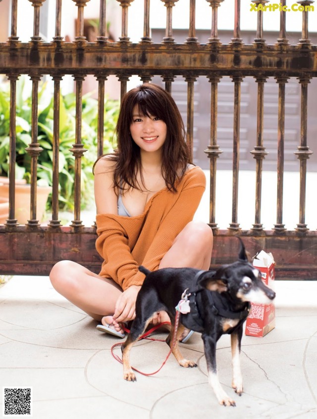 A woman sitting on the ground next to a small dog.