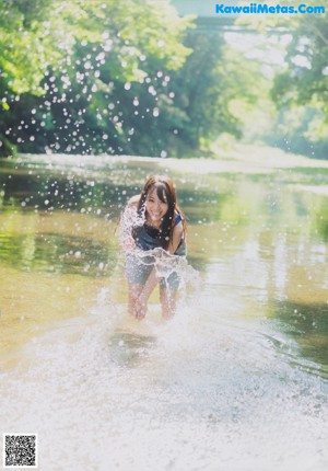 A woman in a blue tank top standing in a river.