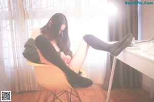 A naked woman sitting on a yellow chair in a room.