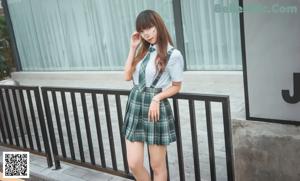 A woman in a school uniform sitting on some steps.
