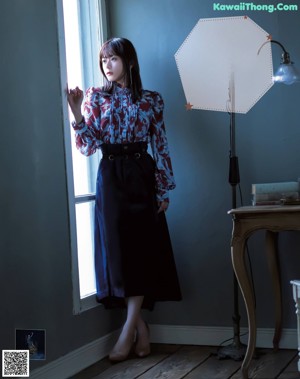 a woman in a purple shirt dress is posing for a magazine