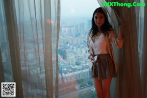A woman in a black lingerie sitting on a window sill.