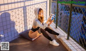 A woman in a black and white bodysuit posing on a balcony.