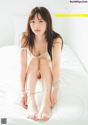 A woman sitting on top of a bed with her legs crossed.