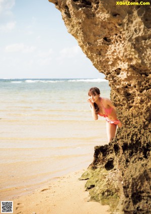 A naked woman holding a shell on the beach.