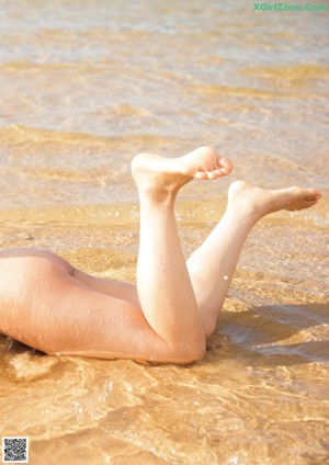 A young girl wrapped in a blanket on the beach.