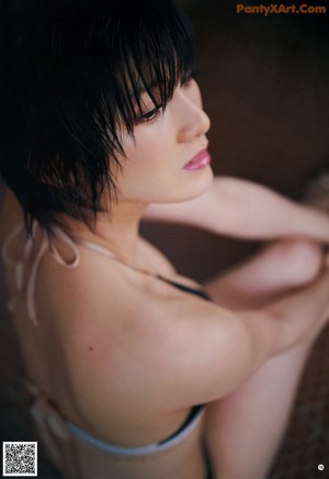 A woman in a bikini sitting on a wooden floor.