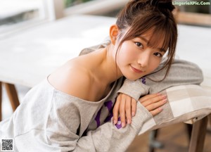 A woman laying on top of a couch next to a pillow.