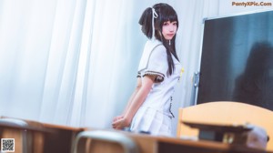 A woman in a school uniform sitting at a desk.