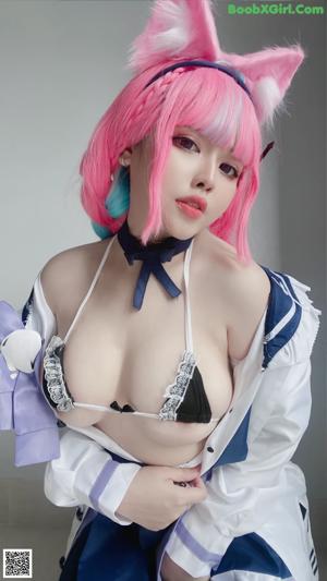 A woman with pink hair wearing a blue and white dress.
