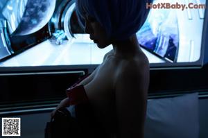 A woman with blue hair wearing a white bodysuit.