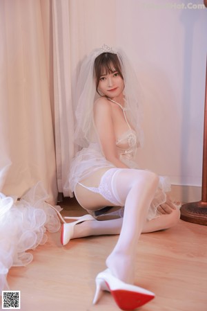 A woman in a wedding dress sitting on the floor.