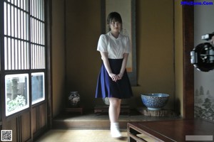 A woman standing in front of a window in a room.