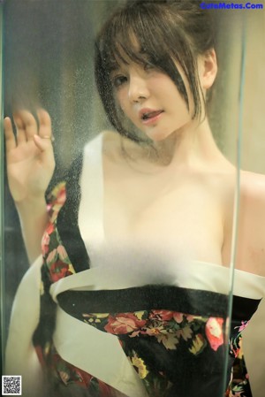 A woman in a kimono standing in front of a glass door.