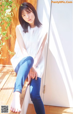 A woman sitting on a window sill with her legs crossed.