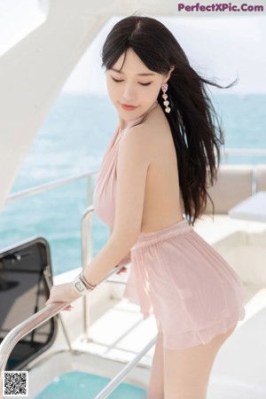 A woman in a pink bathing suit standing on a boat.